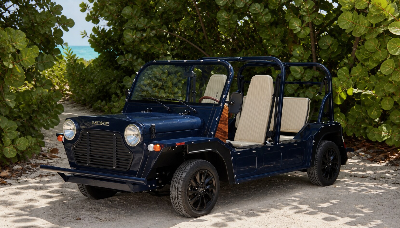 The electric Moke included with every stay, parked on a sandy path near the beach